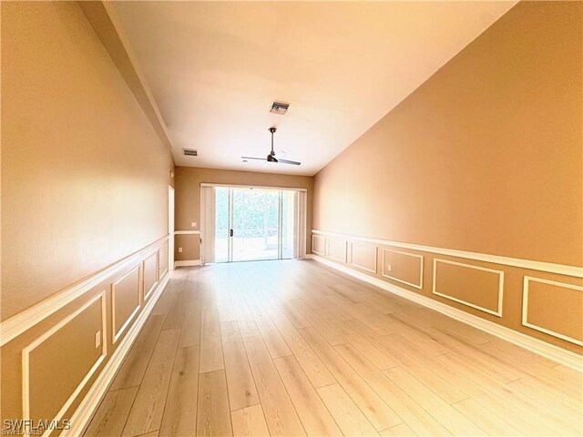 8088 Sanctuary Dr Unit 1, Naples, FL 34104 - empty room with a decorative wall, ceiling fan, light wood-type flooring, and a wainscoted wall