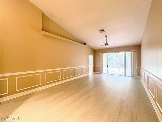 8088 Sanctuary Dr Unit 1, Naples, FL 34104 - empty room featuring a ceiling fan, a decorative wall, a wainscoted wall, wood finished floors, and vaulted ceiling