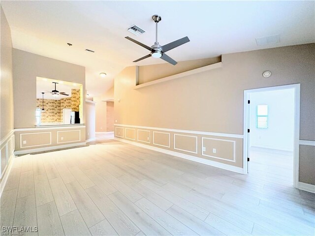 8088 Sanctuary Dr Unit 1, Naples, FL 34104 - unfurnished living room with ceiling fan, vaulted ceiling, wood finished floors, a decorative wall, and wainscoting