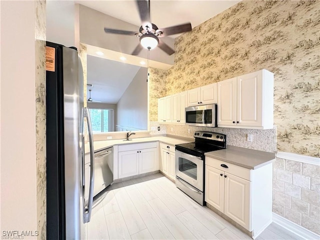 8088 Sanctuary Dr Unit 1, Naples, FL 34104 - kitchen featuring appliances with stainless steel finishes, wallpapered walls, a ceiling fan, white cabinets, and a sink