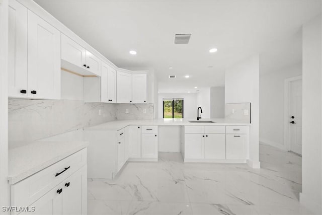1032 Maxwell Ave S, Lehigh Acres, FL 33974 - kitchen with a sink, recessed lighting, light marble finish floors, white cabinets, and decorative backsplash