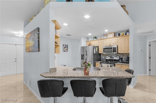 907 SE 19th Ter, Cape Coral, FL 33990 - kitchen with appliances with stainless steel finishes, light brown cabinets, light tile patterned flooring, open shelves, and a breakfast bar