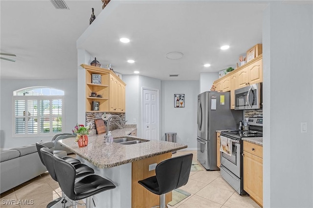 907 SE 19th Ter, Cape Coral, FL 33990 - kitchen featuring appliances with stainless steel finishes, light brown cabinetry, a kitchen breakfast bar, open shelves, and recessed lighting