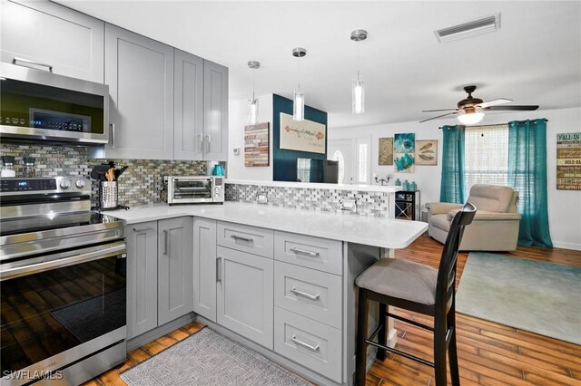 399 Grenier Dr, North Fort Myers, FL 33903 - kitchen with stainless steel appliances, gray cabinets, a peninsula, light wood-type flooring, and light countertops