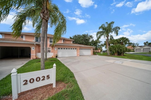 20025 Lake Vista Cir Unit 6B, Lehigh Acres, FL 33936 - traditional home featuring stucco siding, driveway, a front lawn, and a garage