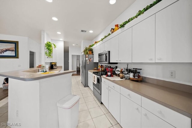 20025 Lake Vista Cir Unit 6B, Lehigh Acres, FL 33936 - kitchen with stainless steel appliances, light tile patterned flooring, white cabinets, a peninsula, and recessed lighting