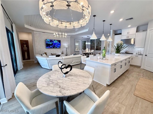 15108 Pescara St, Naples, FL 34114 - dining area featuring a tray ceiling, a chandelier, light wood-style flooring, baseboards, and recessed lighting