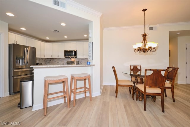9110 Bayberry Bnd Unit 102, Fort Myers, FL 33908 - kitchen featuring appliances with stainless steel finishes, ornamental molding, tasteful backsplash, white cabinetry, and light wood-style flooring