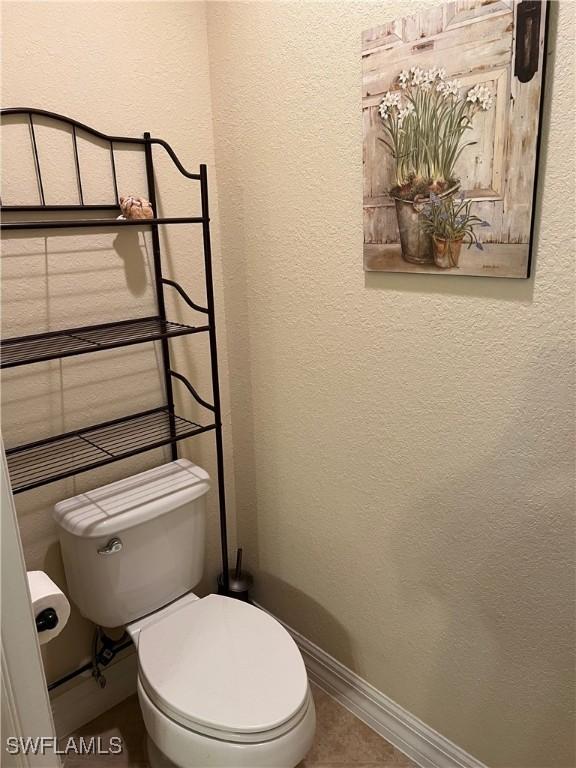 11010 Longwing Dr, Fort Myers, FL 33912 - bathroom with toilet, a textured wall, baseboards, and tile patterned floors