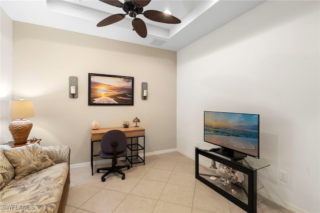 home office featuring a ceiling fan, a tray ceiling, and light tile patterned floors