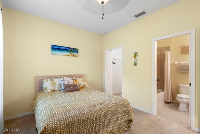 bedroom featuring light colored carpet, a spacious closet, connected bathroom, and light tile patterned floors