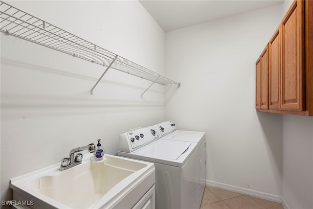 laundry room featuring washer and dryer, cabinet space, and light tile patterned floors