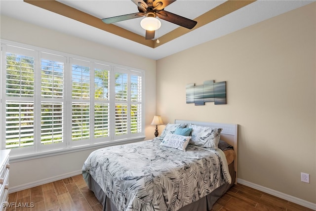 bedroom featuring wood finished floors, a raised ceiling, and ceiling fan