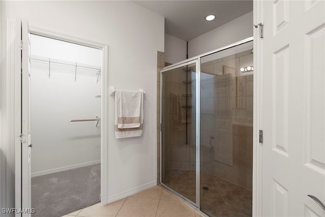 bathroom featuring a walk in closet, a shower stall, tile patterned flooring, and recessed lighting