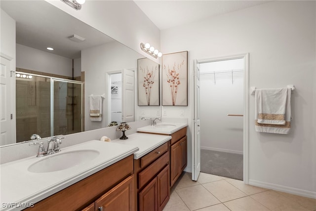 bathroom featuring double vanity, tile patterned flooring, a stall shower, and a spacious closet