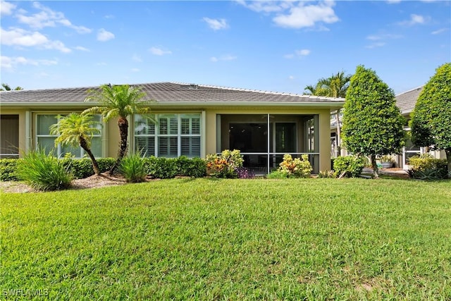 back of house featuring a yard, a sunroom, and stucco siding