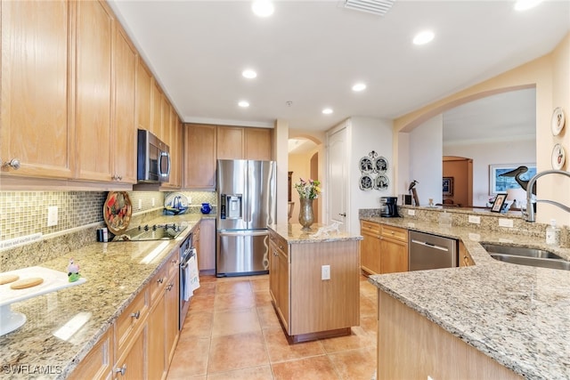 11600 Court Of Palms Unit 301, Fort Myers, FL 33908 - kitchen with appliances with stainless steel finishes, a center island, arched walkways, light stone counters, and crown molding