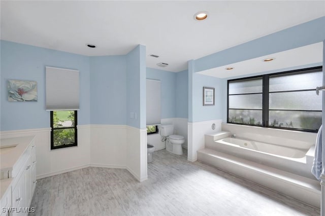 1528 SW 52nd Ln, Cape Coral, FL 33914 - bathroom with wood finished floors, toilet, a wainscoted wall, a bath, and vanity