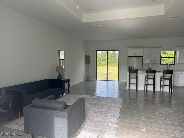 804 W 9th St, Lehigh Acres, FL 33972 - living room with a raised ceiling, baseboards, and light wood-style floors