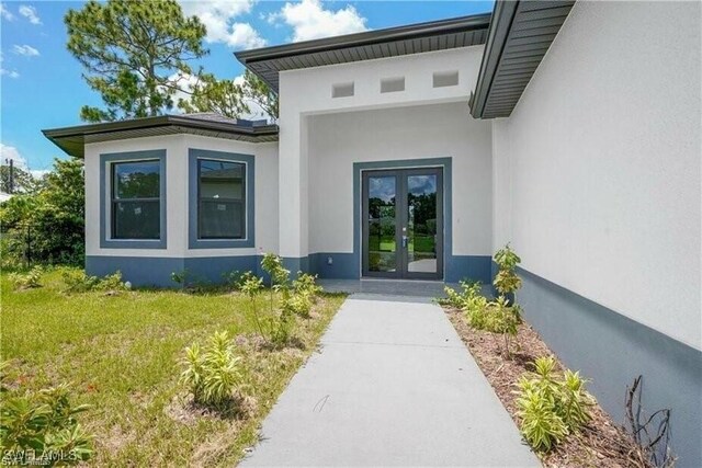 804 W 9th St, Lehigh Acres, FL 33972 - entrance to property featuring french doors, stucco siding, and a yard