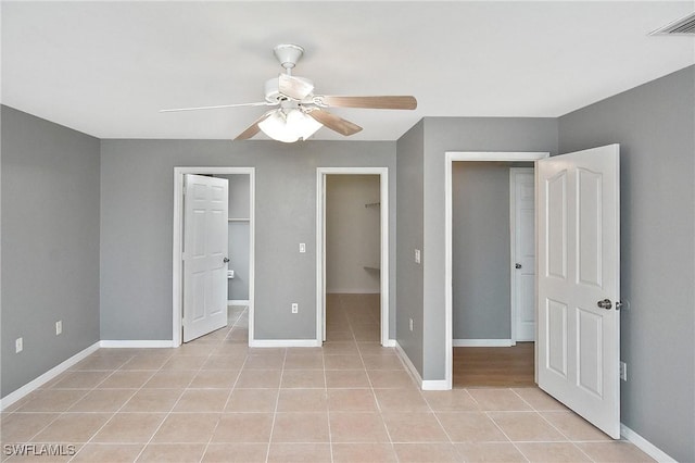 4016 35th St SW, Lehigh Acres, FL 33976 - unfurnished bedroom featuring light tile patterned flooring, baseboards, a walk in closet, and ceiling fan
