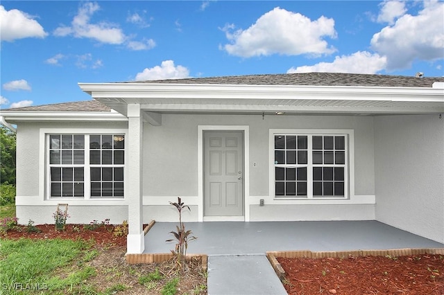 4016 35th St SW, Lehigh Acres, FL 33976 - entrance to property with stucco siding, a shingled roof, and covered porch