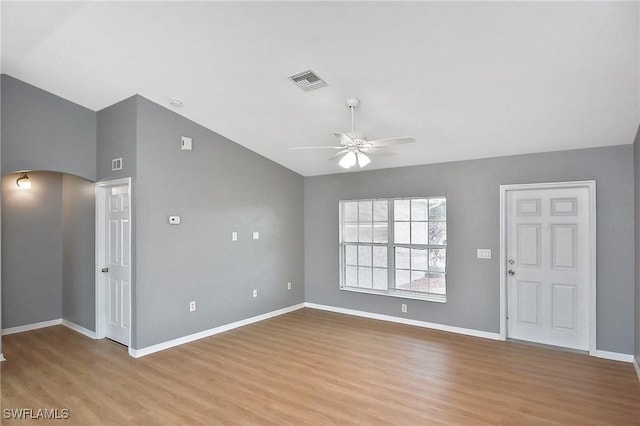 4016 35th St SW, Lehigh Acres, FL 33976 - unfurnished living room featuring ceiling fan, light wood-style flooring, vaulted ceiling, baseboards, and arched walkways