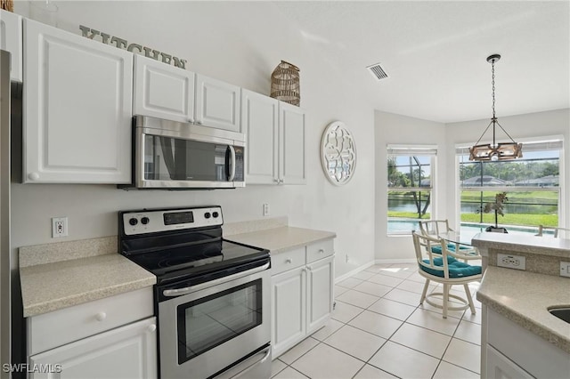 902 Marble Dr, Naples, FL 34104 - kitchen featuring stainless steel appliances, a water view, a chandelier, light tile patterned floors, and light countertops