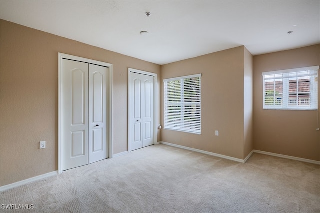 12021 Rock Brook Run Unit 2106, Fort Myers, FL 33913 - unfurnished bedroom with two closets, multiple windows, and carpet