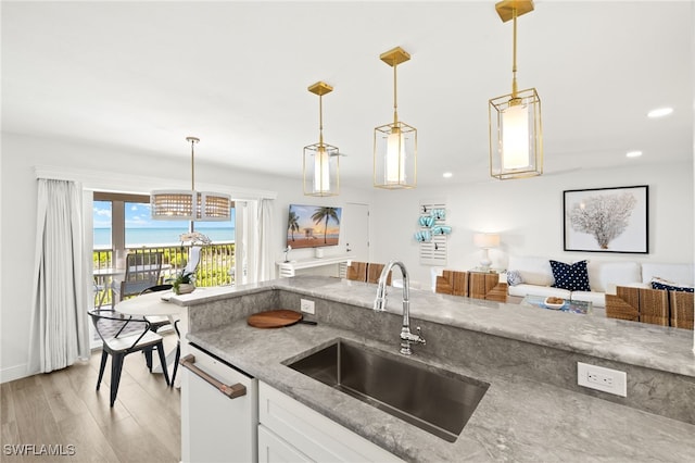 827 E Gulf Dr Unit C6, Sanibel, FL 33957 - kitchen featuring white dishwasher, light wood-style flooring, light stone countertops, pendant lighting, and white cabinets