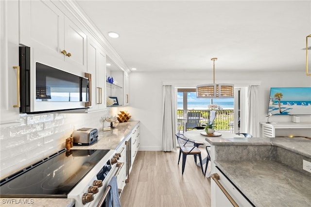 827 E Gulf Dr Unit C6, Sanibel, FL 33957 - kitchen featuring stainless steel range with electric stovetop, white cabinets, light wood-type flooring, tasteful backsplash, and a chandelier