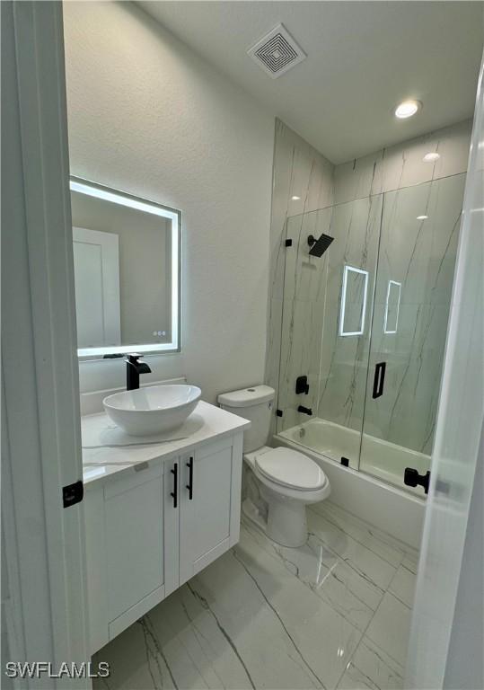 6010 Acorn Cir, Labelle, FL 33935 - full bathroom featuring vanity, bath / shower combo with glass door, toilet, and marble finish flooring