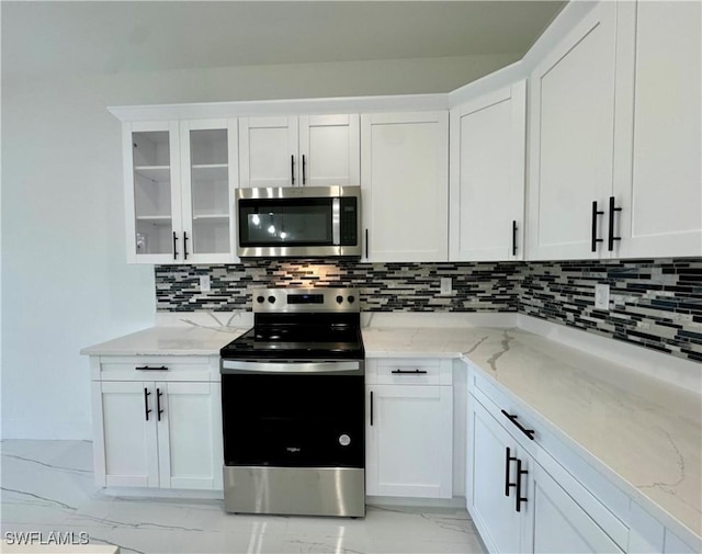 6010 Acorn Cir, Labelle, FL 33935 - kitchen with stainless steel appliances, light marble finish floors, light stone countertops, backsplash, and white cabinetry
