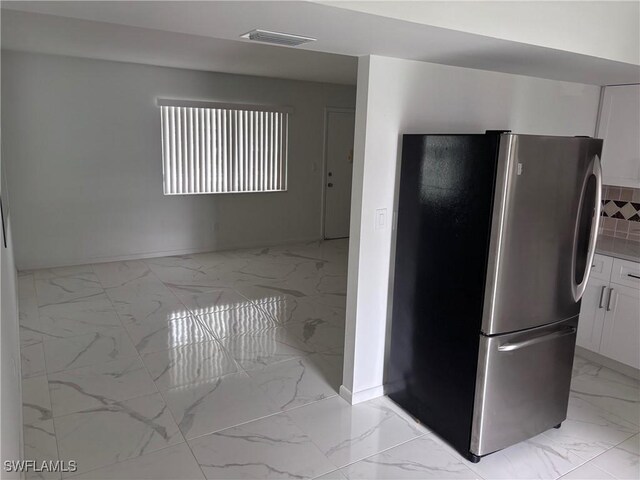 339 Joel Blvd Unit 221, Lehigh Acres, FL 33936 - kitchen featuring freestanding refrigerator, light marble finish flooring, white cabinetry, and baseboards