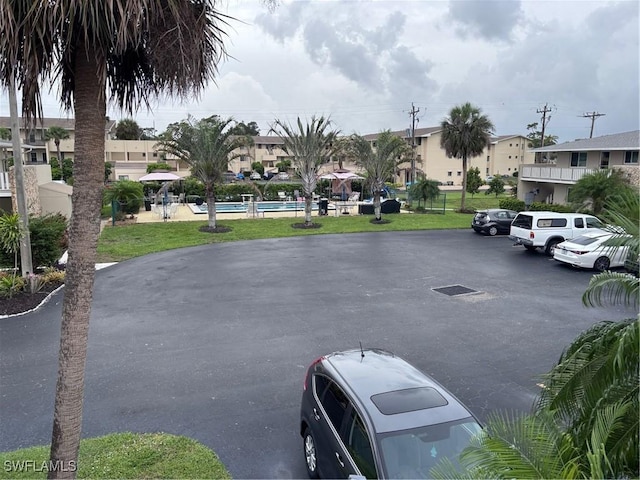 339 Joel Blvd Unit 221, Lehigh Acres, FL 33936 - uncovered parking lot featuring a community pool
