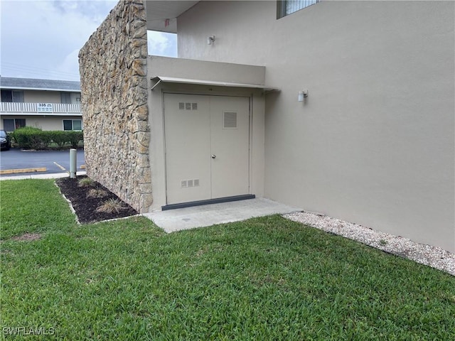 339 Joel Blvd Unit 221, Lehigh Acres, FL 33936 - property entrance with stucco siding, a lawn, and stone siding