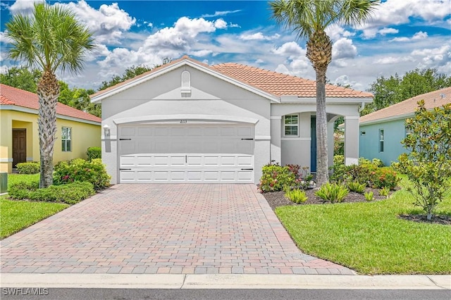 2113 Summersweet Dr, Alva, FL 33920 - mediterranean / spanish home featuring an attached garage, stucco siding, a tile roof, decorative driveway, and a front yard