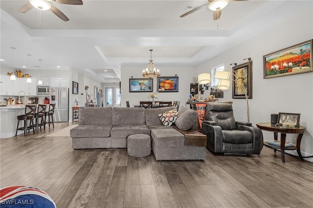 2220 Isle Of Pines Ave, Fort Myers, FL 33905 - living room with a ceiling fan, a tray ceiling, a chandelier, and light wood-style flooring