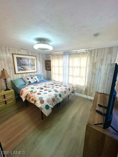 261 Redlin St, North Fort Myers, FL 33903 - bedroom with wood finished floors, wood walls, and a textured ceiling