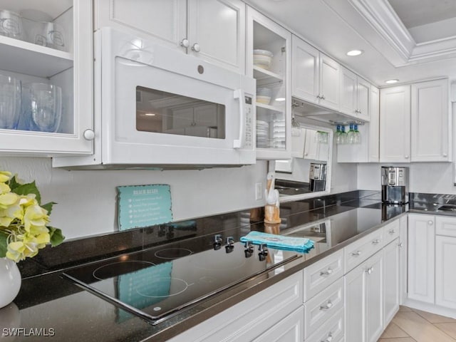 1019 Anglers Cv Unit F302, Marco Island, FL 34145 - kitchen featuring white microwave, black electric stovetop, white cabinetry, glass insert cabinets, and ornamental molding
