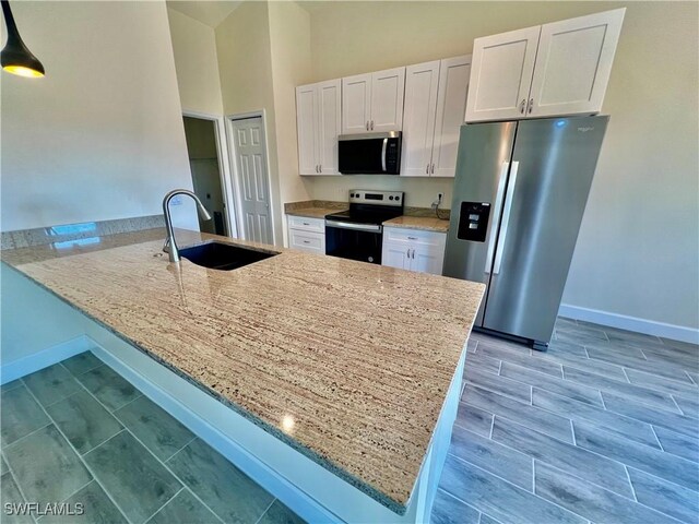 3319 17th St W, Lehigh Acres, FL 33971 - kitchen with stainless steel appliances, a sink, a peninsula, white cabinets, and baseboards