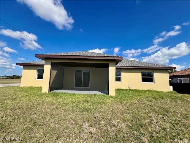3319 17th St W, Lehigh Acres, FL 33971 - back of property with stucco siding, a patio area, and a lawn