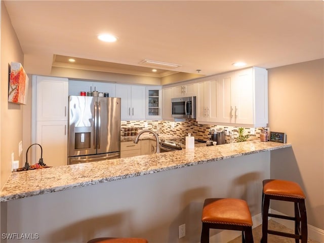 100 N Collier Blvd Unit 803, Marco Island, FL 34145 - kitchen with appliances with stainless steel finishes, a peninsula, decorative backsplash, light stone countertops, and crown molding