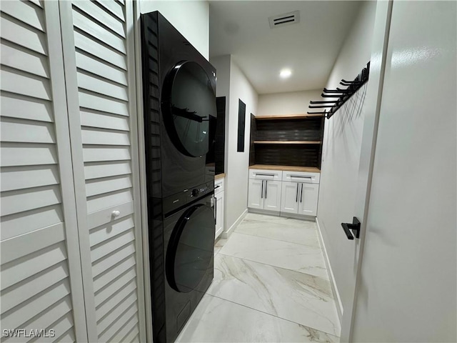 780 Augusta Blvd Unit C204, Naples, FL 34113 - laundry room featuring stacked washer and clothes dryer, light marble finish floors, cabinet space, and baseboards