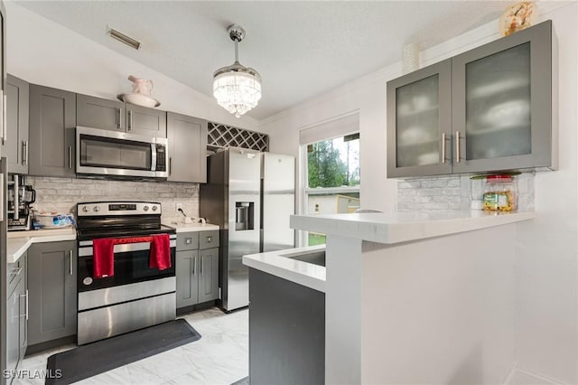 503 E 13th St, Lehigh Acres, FL 33972 - kitchen with appliances with stainless steel finishes, gray cabinetry, tasteful backsplash, and light countertops