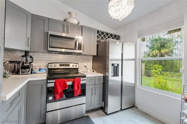 503 E 13th St, Lehigh Acres, FL 33972 - kitchen with appliances with stainless steel finishes, gray cabinets, vaulted ceiling, light countertops, and backsplash