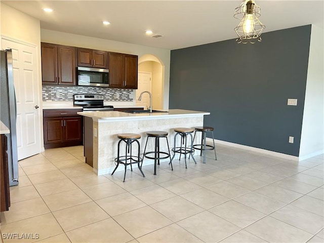 406 SW 25th Pl, Cape Coral, FL 33991 - kitchen featuring stainless steel appliances, a sink, arched walkways, a breakfast bar area, and light countertops