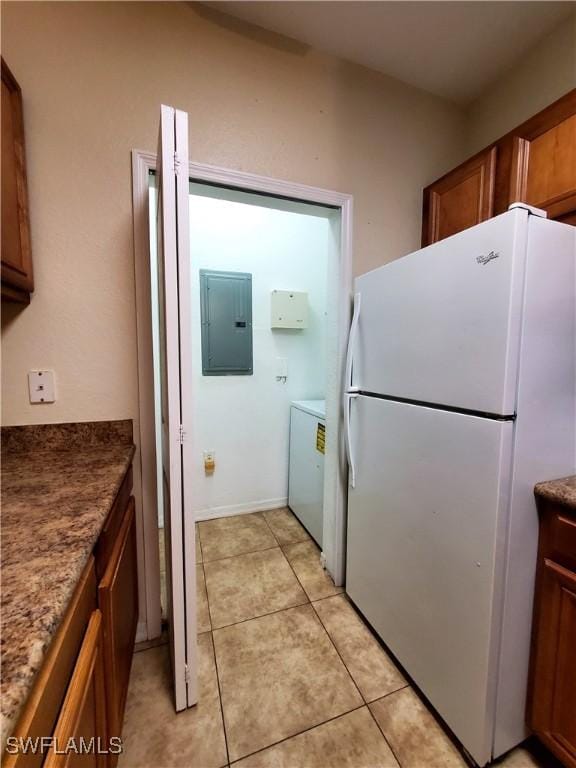 6169 Metrowest Blvd Unit 104, Orlando, FL 32835 - kitchen with freestanding refrigerator, electric panel, brown cabinets, washer / dryer, and light tile patterned flooring