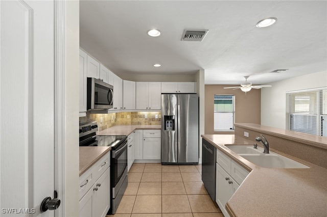 2933 NW 25th Ter, Cape Coral, FL 33993 - kitchen featuring appliances with stainless steel finishes, backsplash, light tile patterned flooring, white cabinets, and light countertops