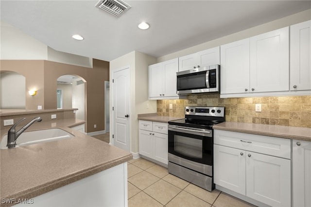 2933 NW 25th Ter, Cape Coral, FL 33993 - kitchen featuring stainless steel appliances, arched walkways, light tile patterned floors, tasteful backsplash, and white cabinets